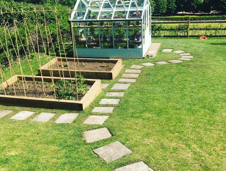 After: levelled kitchen garden with greenhouse, raised beds and stepping-stone path in Rudry