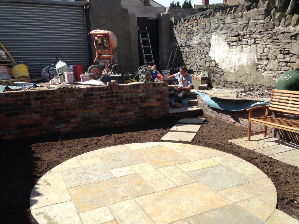 During: circular patio set out with fresh topsoil beds and bench seating