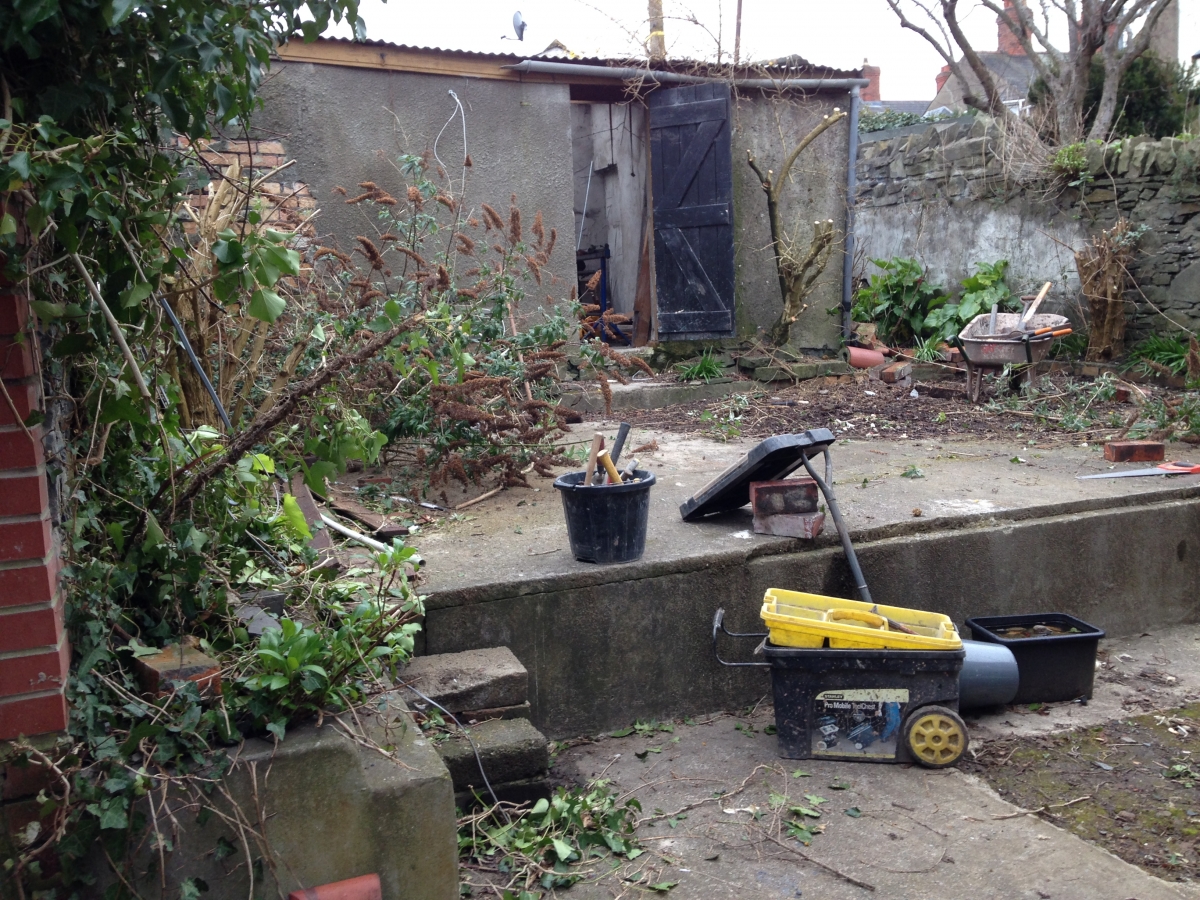 Before: overgrown walls and rubble across the two-level concrete pad