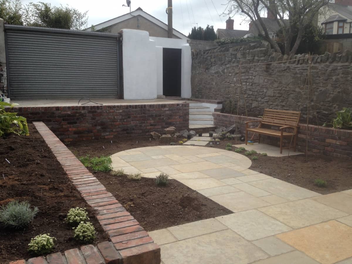 Albany Road: a circular stone patio with curved brick-edged beds and reclaimed stone walling.