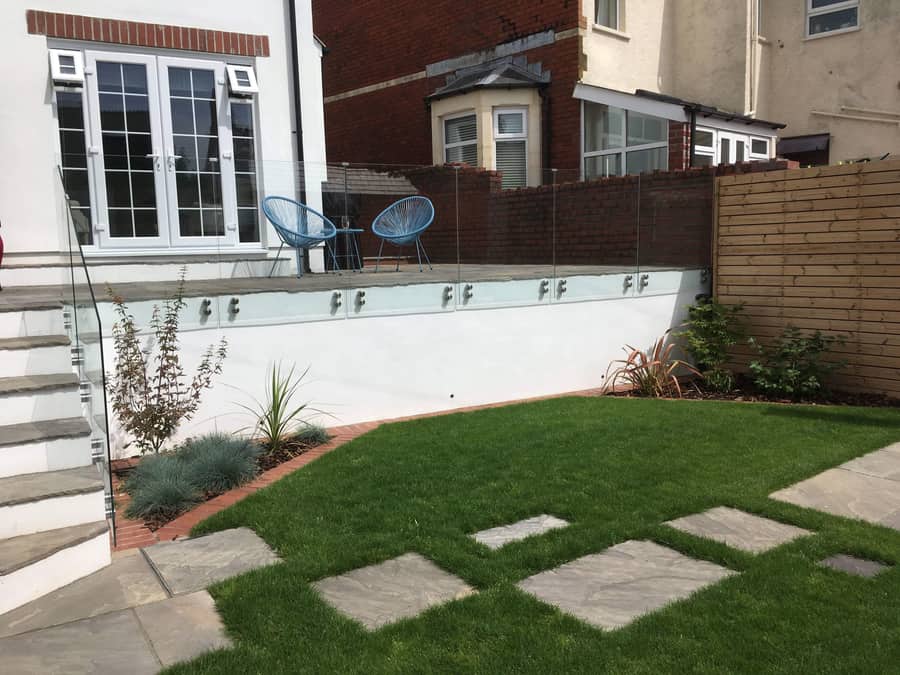 A crisp family garden with white rendered walls, level lawn and stepping stones.